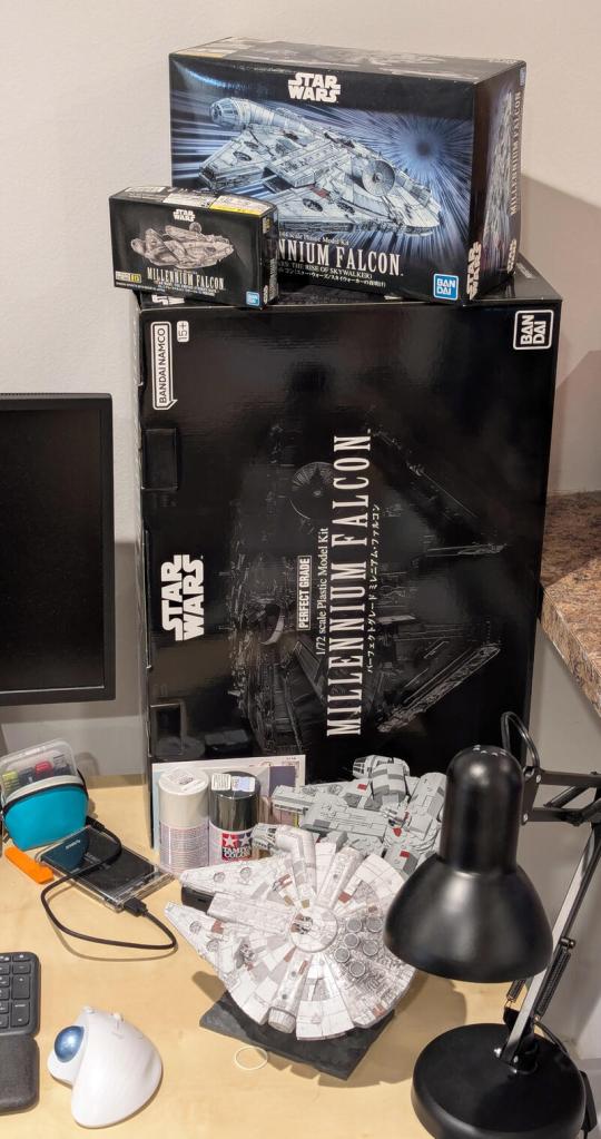 Star Wars vintage and modern action figures and vehicles on a bookshelf and desk.