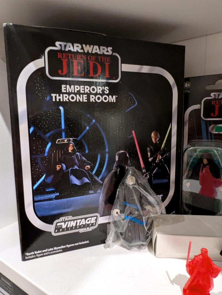 Star Wars vintage and modern action figures and vehicles on a bookshelf and desk.